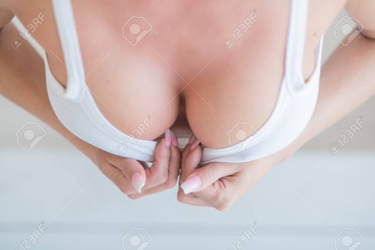 Sexy Woman Shows Off Her Big Silicone Breasts By Pulling Off Her White Top With Her Hands On A White Background. Beautiful Elastic Breasts Perfect Shape Stock Photo Picture and Royalty Free