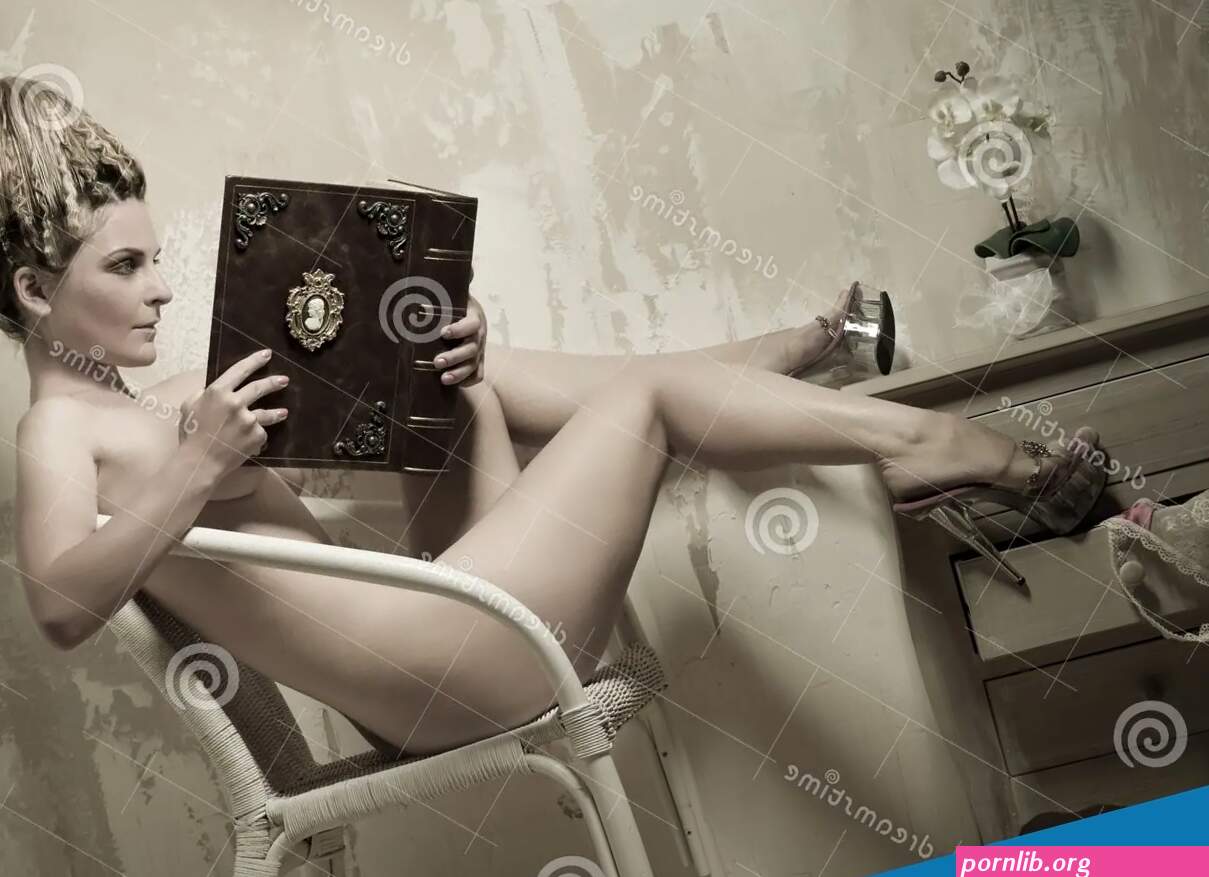 Naked Woman Sitting in a Chair and Reading a Book Stock Photo